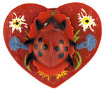 “SHIRLEY TEMPLE” PLASTIC HEART-SHAPED PIN WITH HIGH RELIEF LADYBUG COVER.