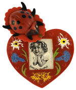 “SHIRLEY TEMPLE” PLASTIC HEART-SHAPED PIN WITH HIGH RELIEF LADYBUG COVER.