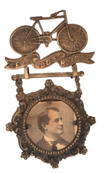 "FOR GOOD ROADS" SHELL BADGE WITH BRYAN PORTRAIT AND FIGURAL BICYCLE.
