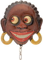 BLACK AFRICAN WITH SPINNING EYEBALLS LITHO TIN MECHANICAL BADGE.