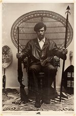 ICONIC BLACK PANTHER PARTY POSTER FEATURING HUEY NEWTON IN FAN-BACKED RAFFIA CHAIR.