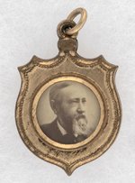 HARRISON & MORTON BACK-TO-BACK BRASS SHELL SHIELD JUGATE CHARM.