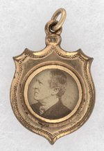 HARRISON & MORTON BACK-TO-BACK BRASS SHELL SHIELD JUGATE CHARM.