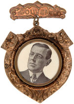 WILSON ENCASED CELLULOID ON EMBOSSED BRASS "SOUVENIR" BADGE.